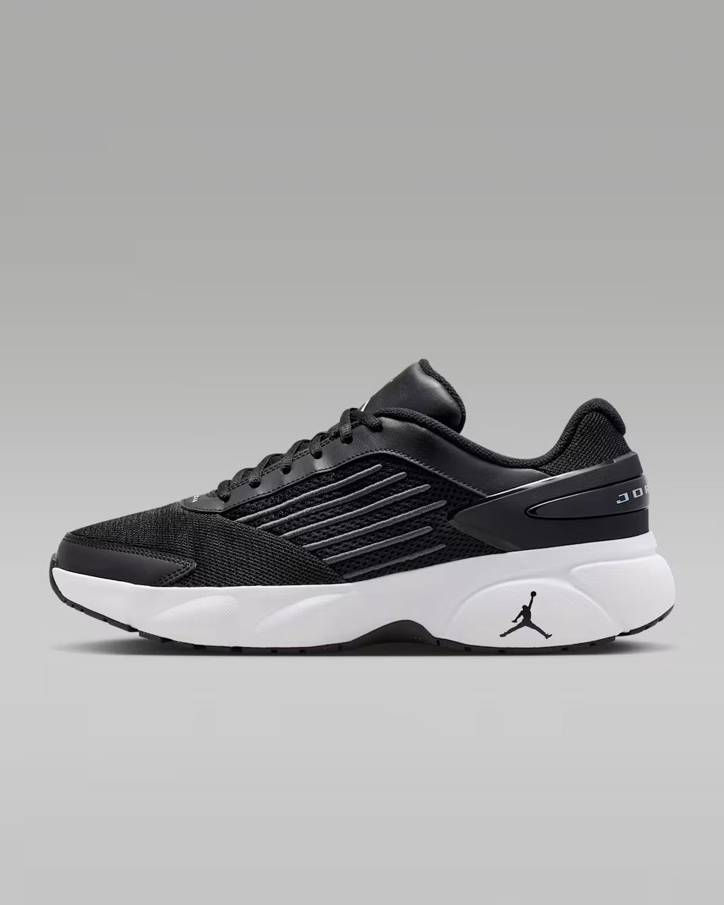 Black athletic shoe with white sole on a gray background