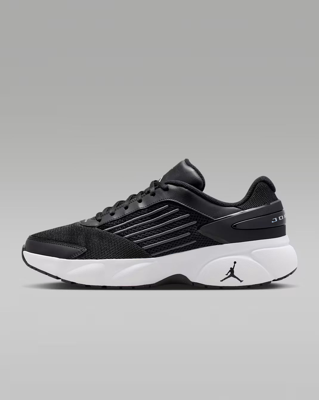 Black athletic shoe with white sole on a gray background